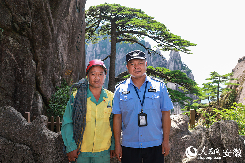全国道德模范李培生（左）和胡晓春在迎客松前合影。人民网记者 张俊摄